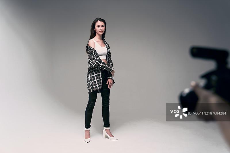 模特在拍摄现场的后台。一位年轻女性站在环幕前。图片素材