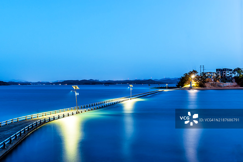 黄昏时分宁静的桥梁横跨平静的水面图片素材