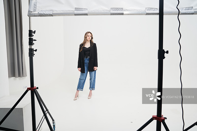 模特在拍摄现场的后台。一位年轻女性站在环幕前。图片素材