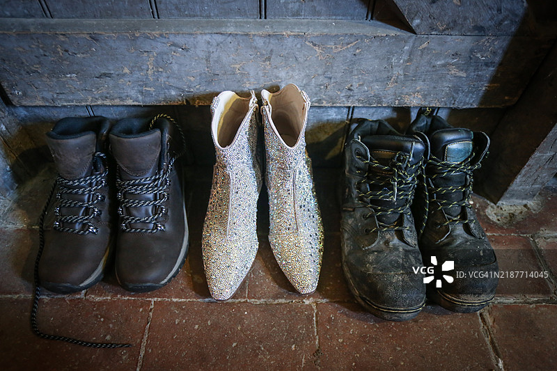 闪亮的 ankle boots 与肮脏的暗淡工作靴并排放置图片素材