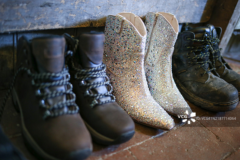 闪亮的 ankle boots 和肮脏的暗淡工作靴并排放置图片素材