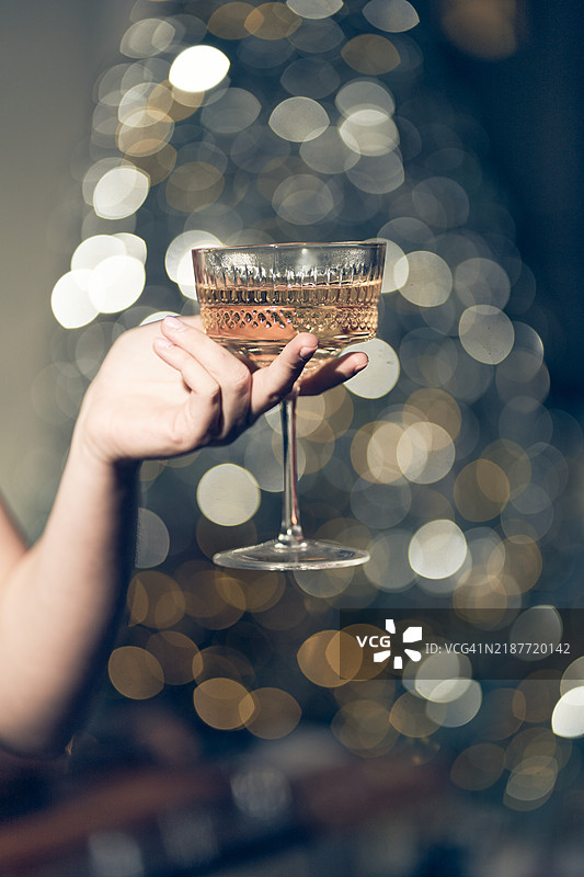 一位女性手中的一杯酒。美丽的散景，节日的饮品。图片素材