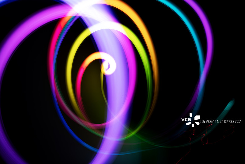 五光十色的光轨在夜间活动中形成迷人的漩涡，伴随着生动的运动效果图片素材