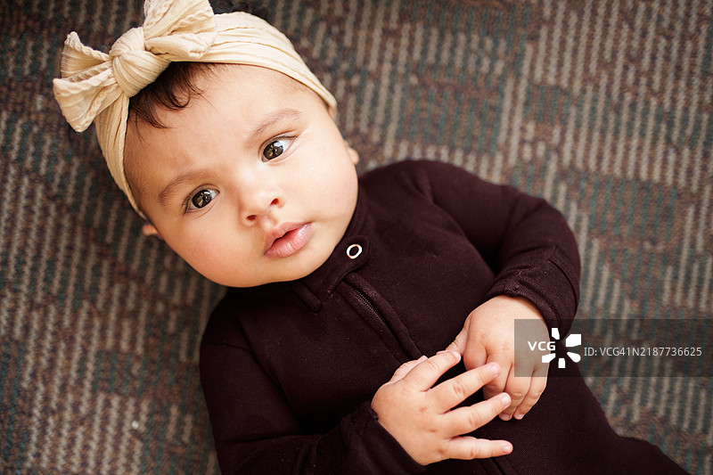 可爱的婴儿戴着头带，躺在图案地毯上图片素材