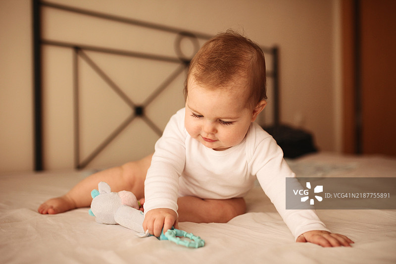 美丽的小女孩在柔和的光线下微笑着躺在床上图片素材