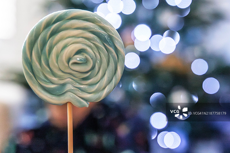 一颗棒棒糖的特写，背景是灯光闪烁。图片素材