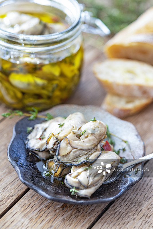 油浸腌制生蚝与新鲜面包在乡村风格的桌子上图片素材