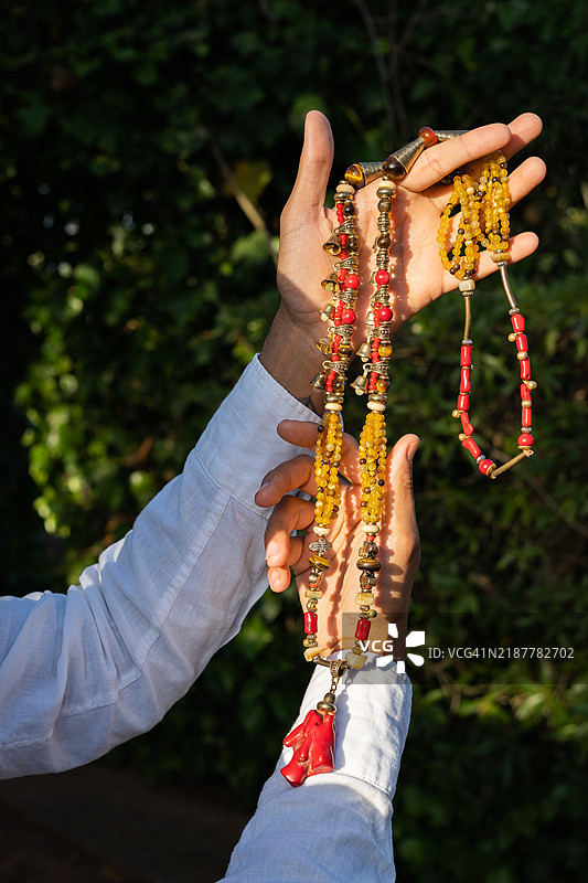 男子展示色彩斑斓的手工项链图片素材