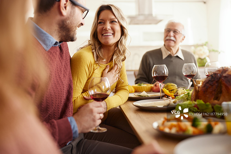快乐的女人在餐桌上与丈夫和年长的父亲共进午餐时交谈。图片素材
