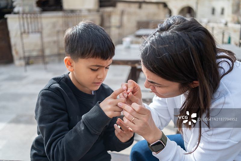 女人用镊子拔出孩子手中的刺图片素材