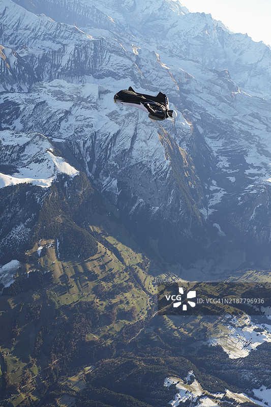 翼装飞行者在雪山上空仰面飞翔图片素材