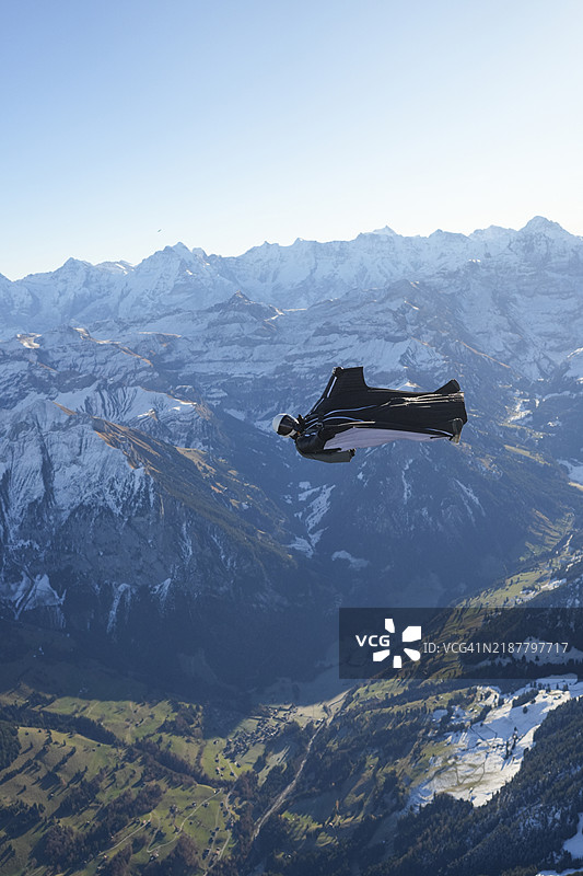 翼装飞行者在雪山上空仰面飞翔图片素材
