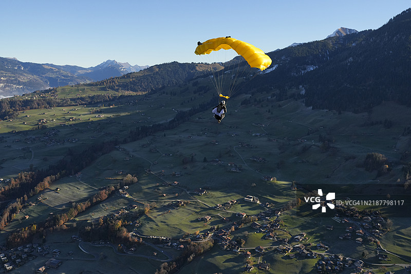 滑翔伞在瑞士阿尔卑斯山的郁郁葱葱的山谷上空翱翔图片素材