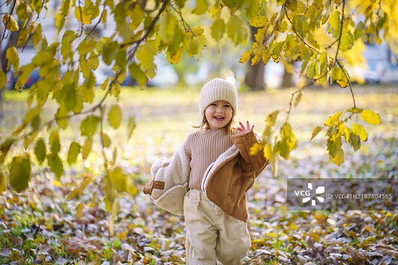 快乐的女孩在秋天的公园里奔跑图片素材