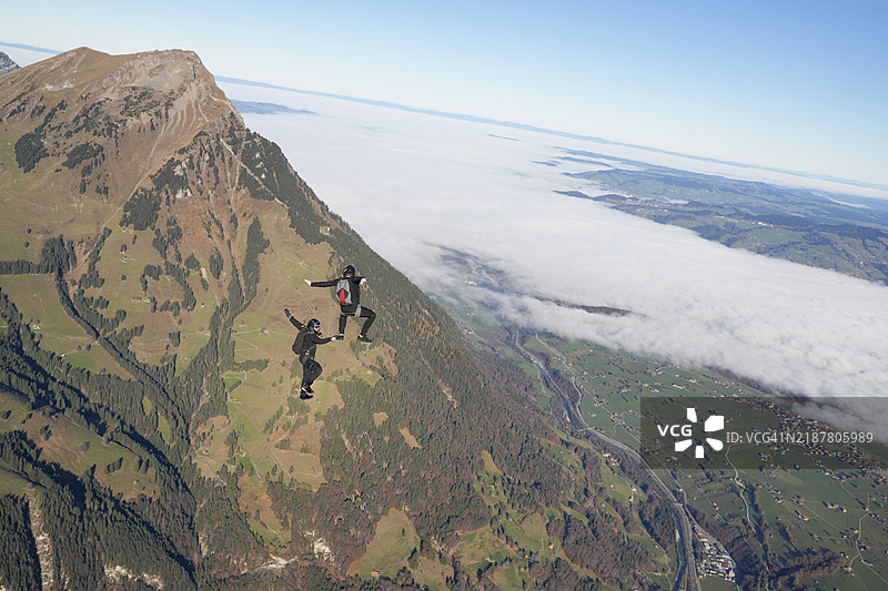 跳伞者在山脉上表演特技图片素材
