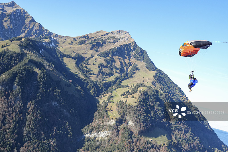 滑翔伞在瑞士阿尔卑斯山的郁郁葱葱的山谷上空翱翔图片素材