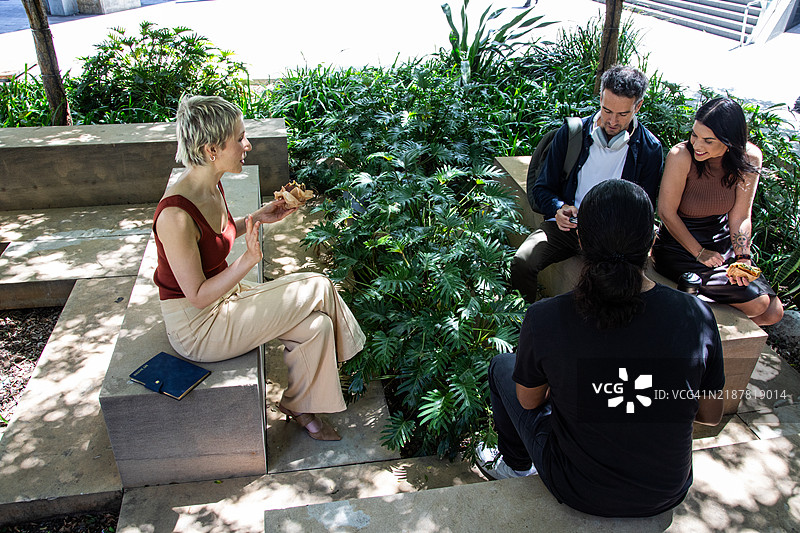 一群人在户外吃饭和交谈。图片素材