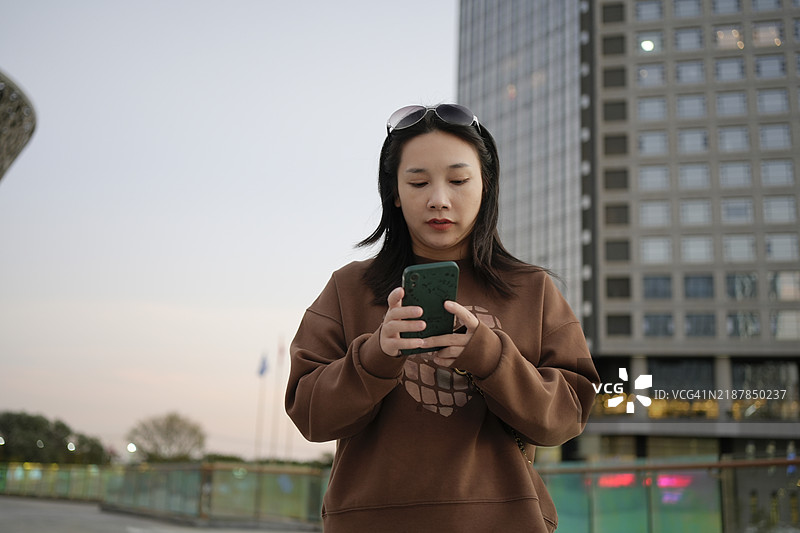 美丽的女商人微笑着在办公室外使用智能手机图片素材