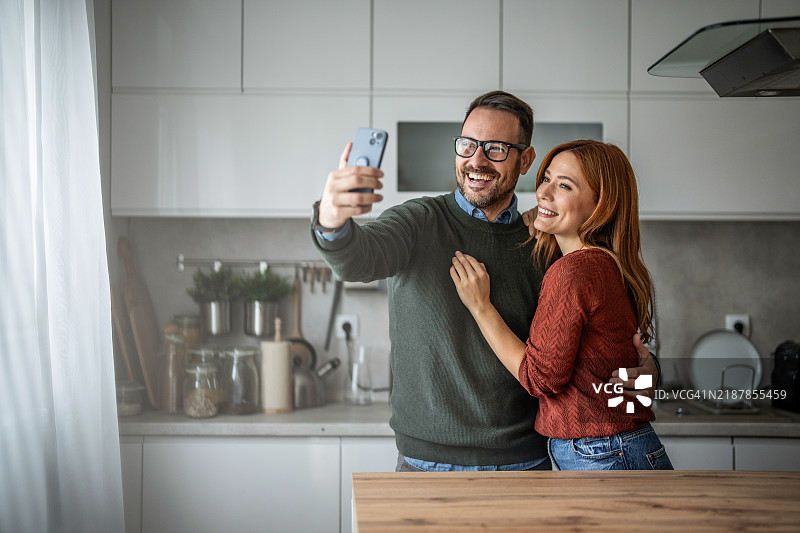 迷人的情侣在厨房里用自拍记录美好回忆图片素材