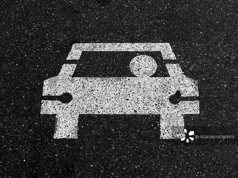 巴黎街道上黑色沥青上涂有白色拼车标志。粗糙的纹理。阳光。单色。图片素材