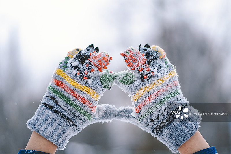 五彩缤纷的针织手套在冬季雪景中被双手握住图片素材