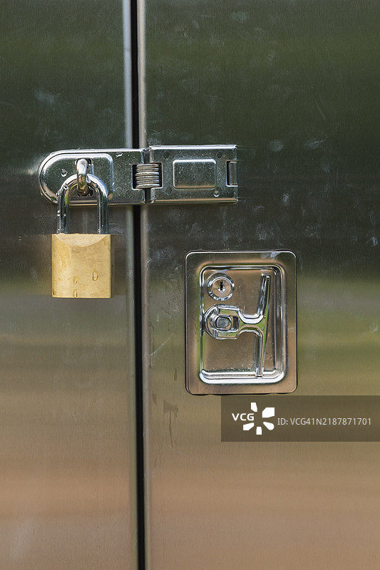 不锈钢门的特写，锁在一个带有黄铜挂锁的工具柜上，加拿大魁北克，北美图片素材