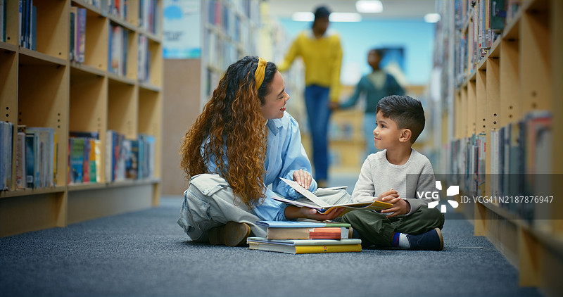 快乐的孩子，图书馆里老师在地板上给学生读书，帮助学习和展示学校的文学。孩子、女性和教育与图书管理员一起获取知识、学习建议和发展。图片素材