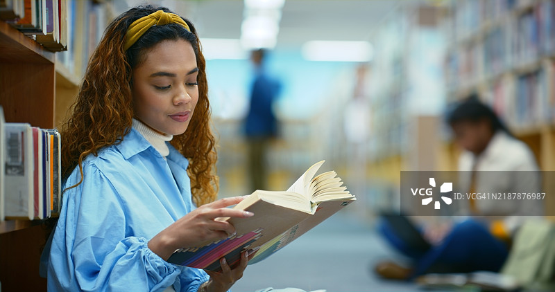 大学生在图书馆阅读书籍，女孩在学习、上课或进行研究。大学、书架和拿着教科书的女性，进行教育、知识或为考试学习信息。图片素材