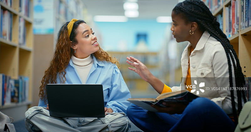 图书馆里的教育、朋友和女性，使用笔记本电脑进行团队作业，交流想法和互联网。大学生们在地板上，使用电脑进行网络交流、研究或学习。图片素材