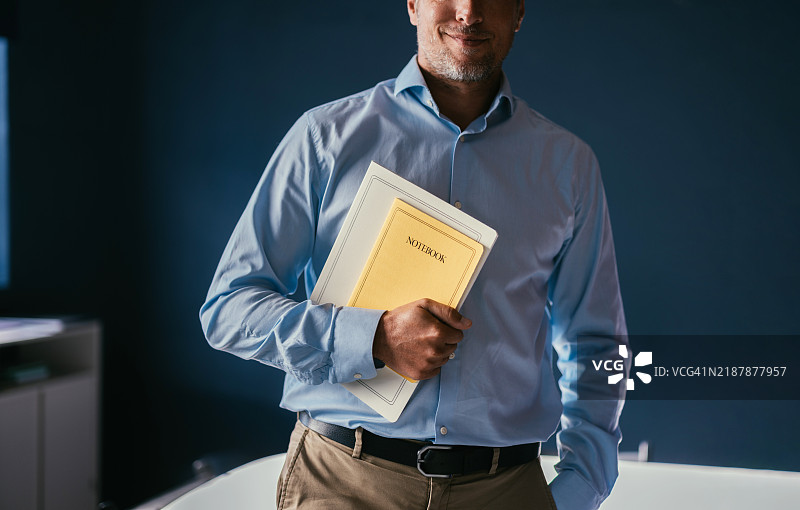 自信的商人手持笔记本站在办公室里图片素材