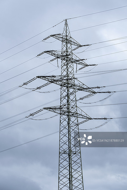高压电塔矗立在多云的天空前图片素材