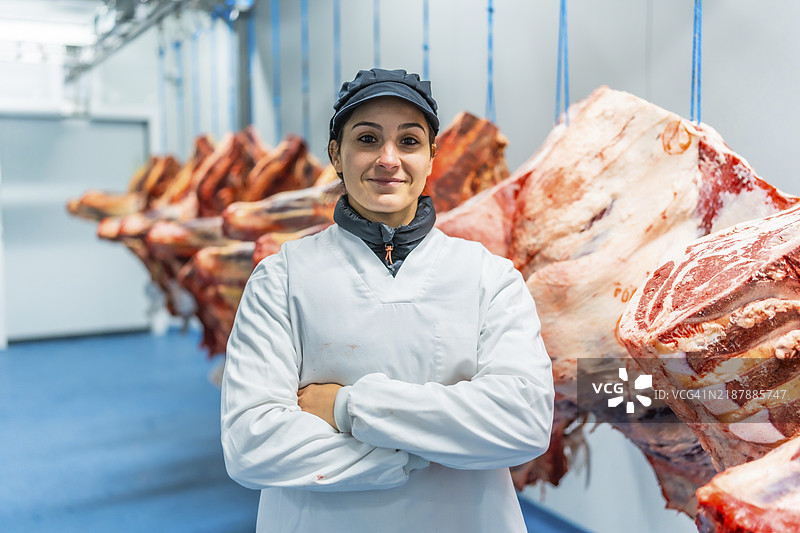 一位女性工人在肉类工厂的冷藏室里自豪地站着图片素材