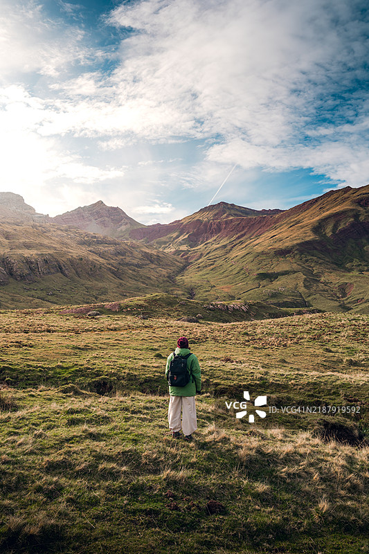 一位穿着温暖的女性在思考阿拉贡比利牛斯山的阿瓜斯图尔塔斯山谷的风景。图片素材