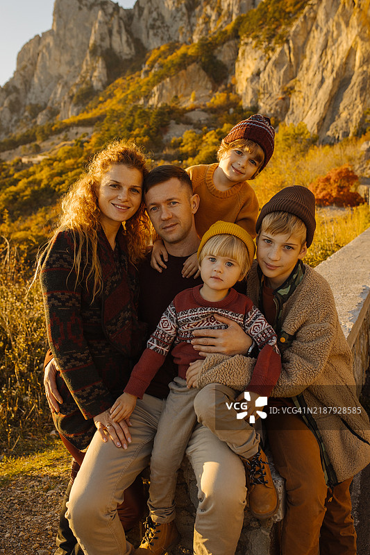 一家五口穿着时尚的温暖衣物，父亲、母亲和三个兄弟以及一只狗在户外享受他们的冒险，露营和徒步旅行。图片素材