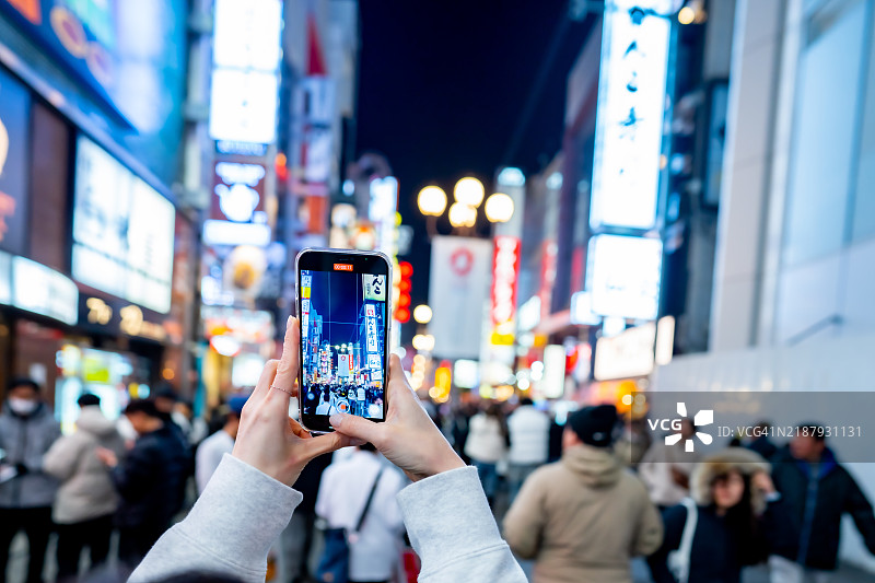 游客在日本大阪市心斋桥的道顿堀夜市街头品尝美食。图片素材