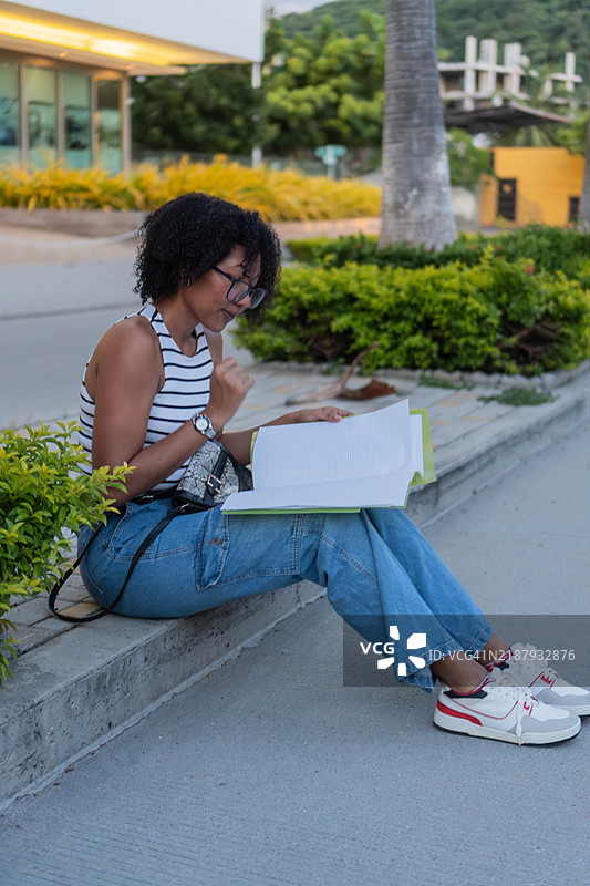 年轻学生在校园人行道上阅读一本书图片素材