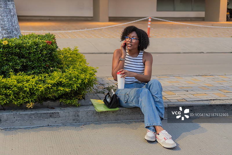 年轻女性坐在人行道上打电话图片素材