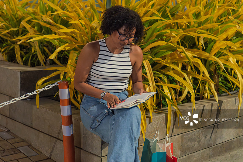 年轻女性在购物后阅读一本书图片素材