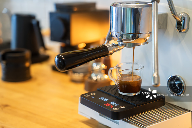 浓缩咖啡从咖啡机倒入木质台面的玻璃杯中图片素材