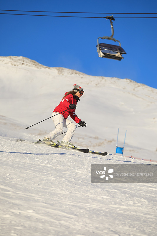 积极的生活方式，女性滑雪者在完美的滑雪坡道上高速滑雪，享受阳光明媚的塞拉隆达滑雪度假区。多洛米蒂超级滑雪区的雪山。意大利瓦尔加尔德纳滑雪度假村。图片素材