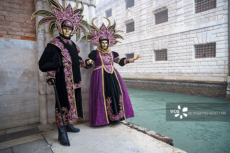 在威尼斯狂欢节上，一对戴着面具的情侣在总督宫的拱廊下。图片素材