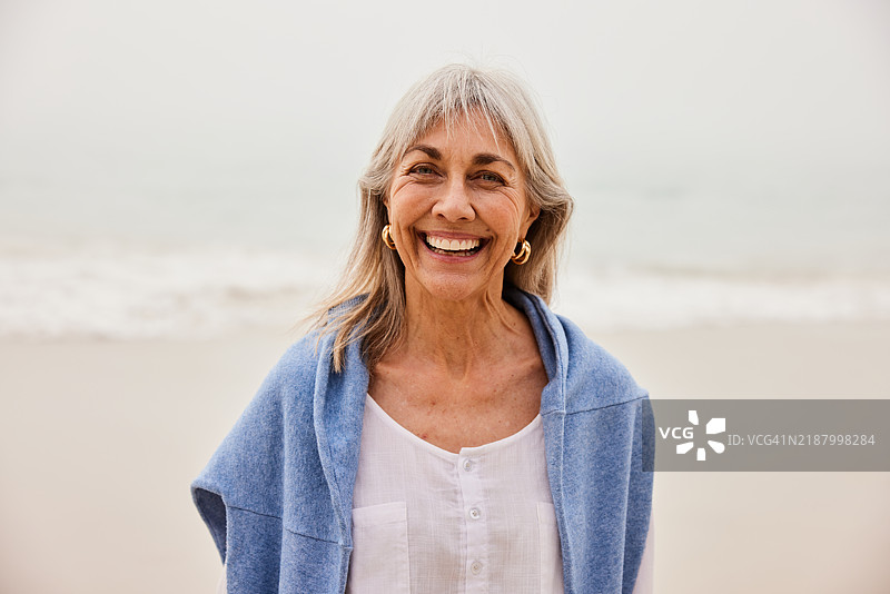 自然美丽的老年女性在空旷的海滩上微笑着看向镜头图片素材