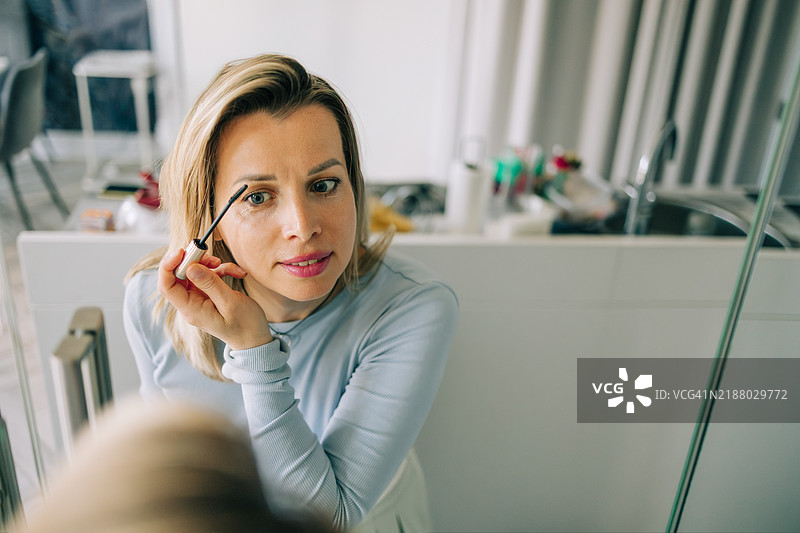 中年女性在镜子前涂抹睫毛膏图片素材