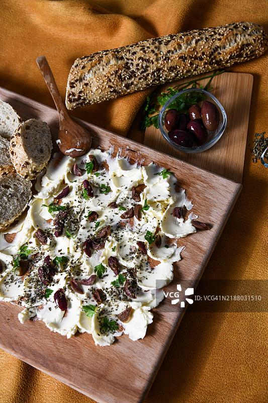 美味的开胃菜：黄油涂抹在木板上，上面撒有咸味配料图片素材