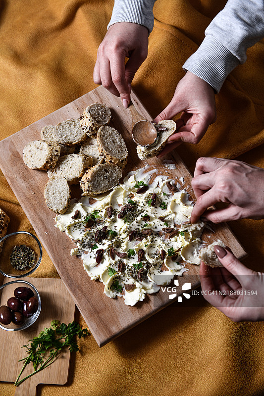 朋友们在法棍片上涂抹黄油，享受美味的开胃小吃图片素材
