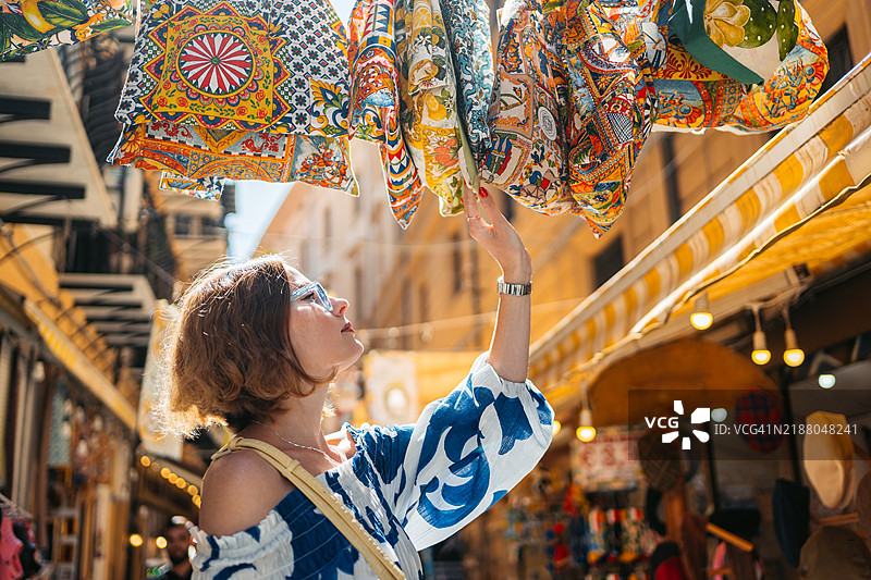 中年女性在意大利巴勒莫的街市上购物，挑选围巾图片素材