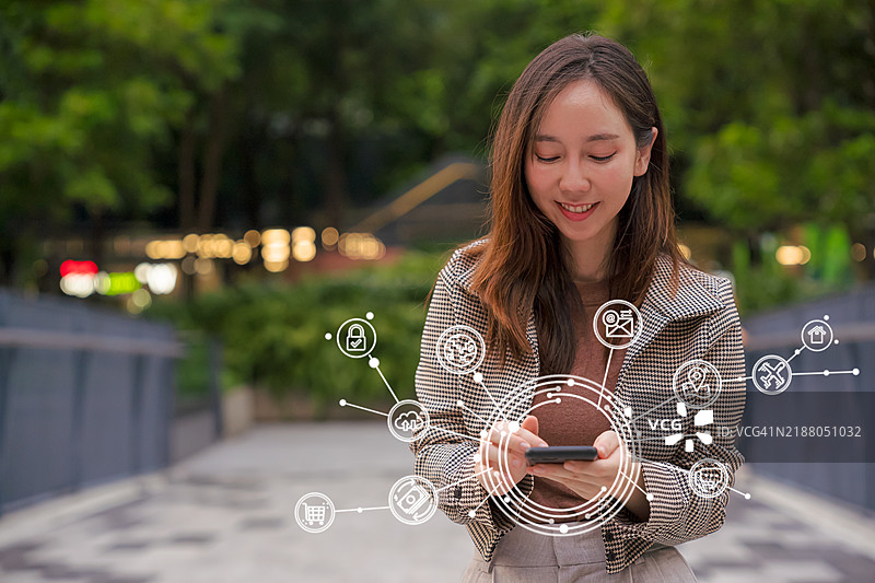 商务女性使用智能手机，周围虚拟显示各种智能手机技术图标。人工智能与通信网络概念。图片素材
