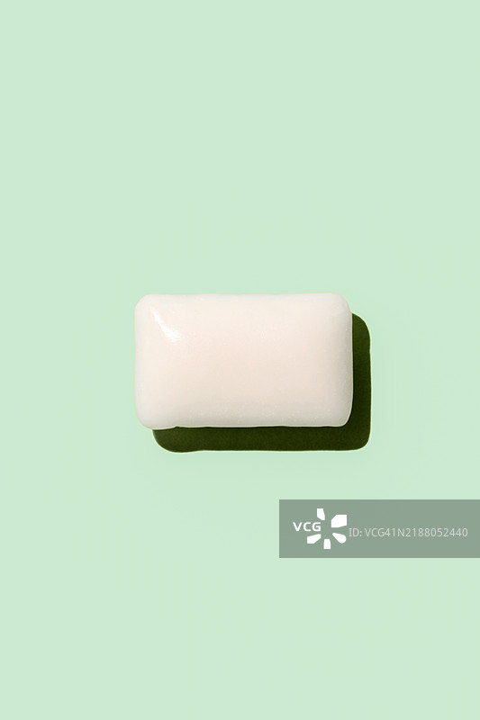 一块白色口香糖置于鲜艳的绿色背景上，形成视觉上引人注目的特写镜头图片素材