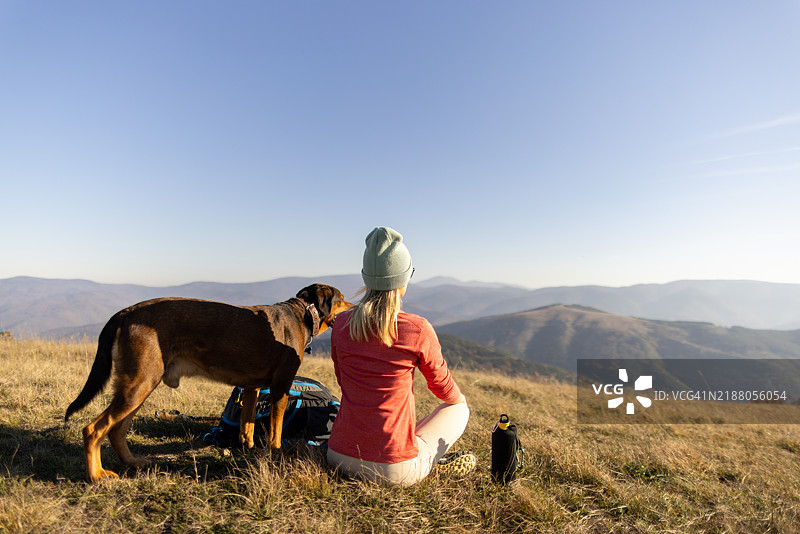 女人和她的狗在远足中休息图片素材