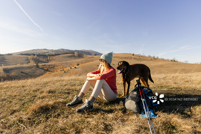 女人和她的狗在远足中休息图片素材